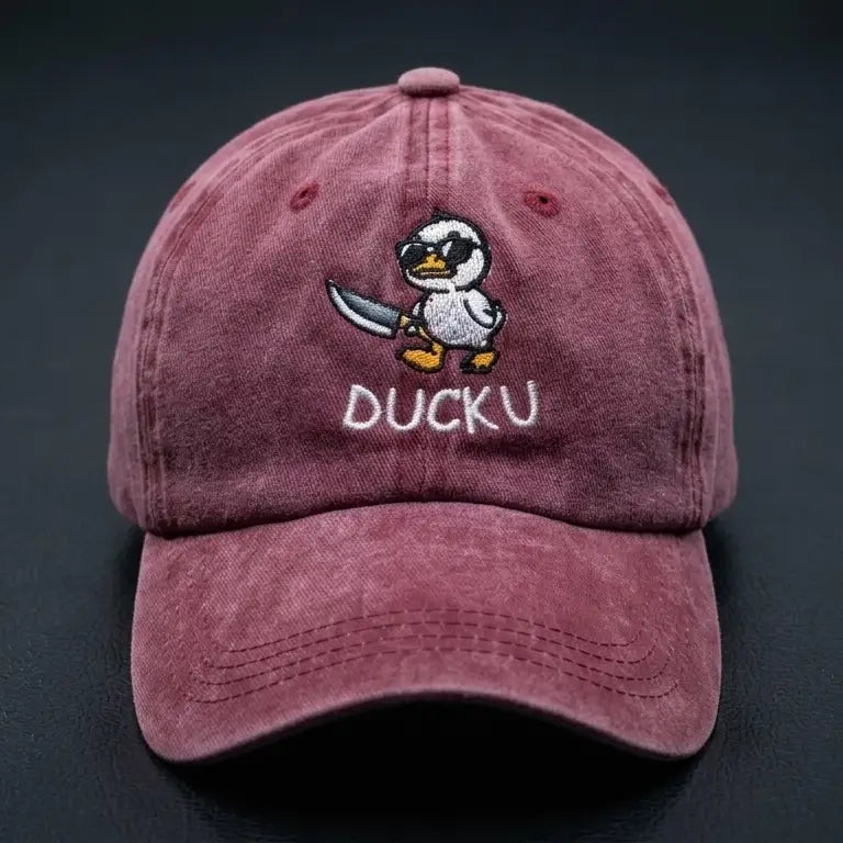 A Burghandy baseball cap featuring an embroidered cartoon duck character holding a sword and the text 'DUCKU' on the front, set against a dark textured background.